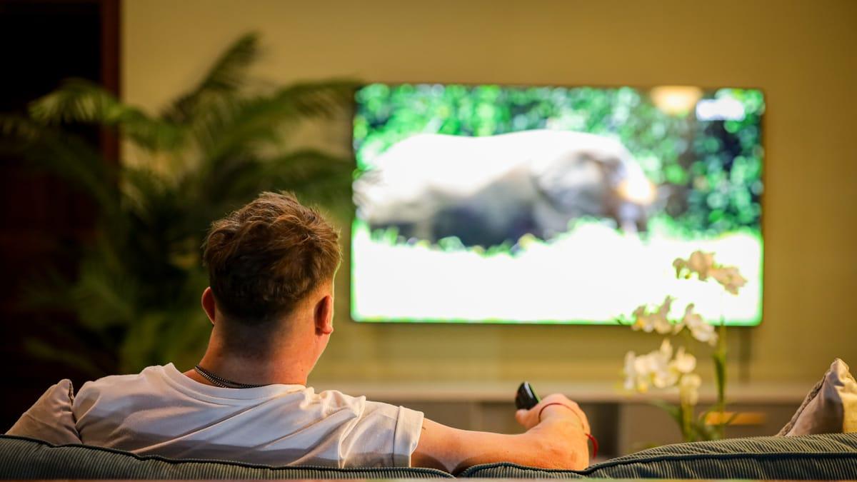 A man relaxes on a sofa watching television in the lounge at Jintara Rehab in Chiang Mai