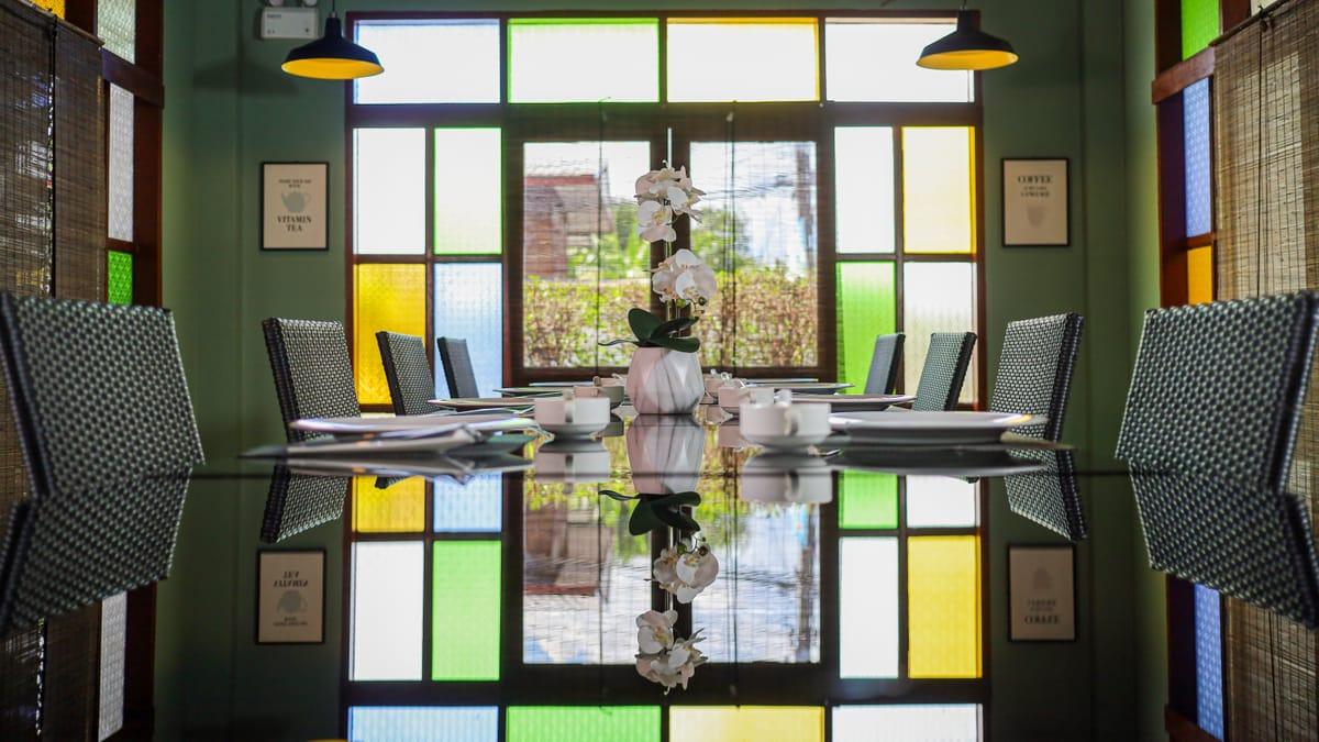 The dining room with stained-glass windows and a set table at Jintara Rehab in Chiang Mai