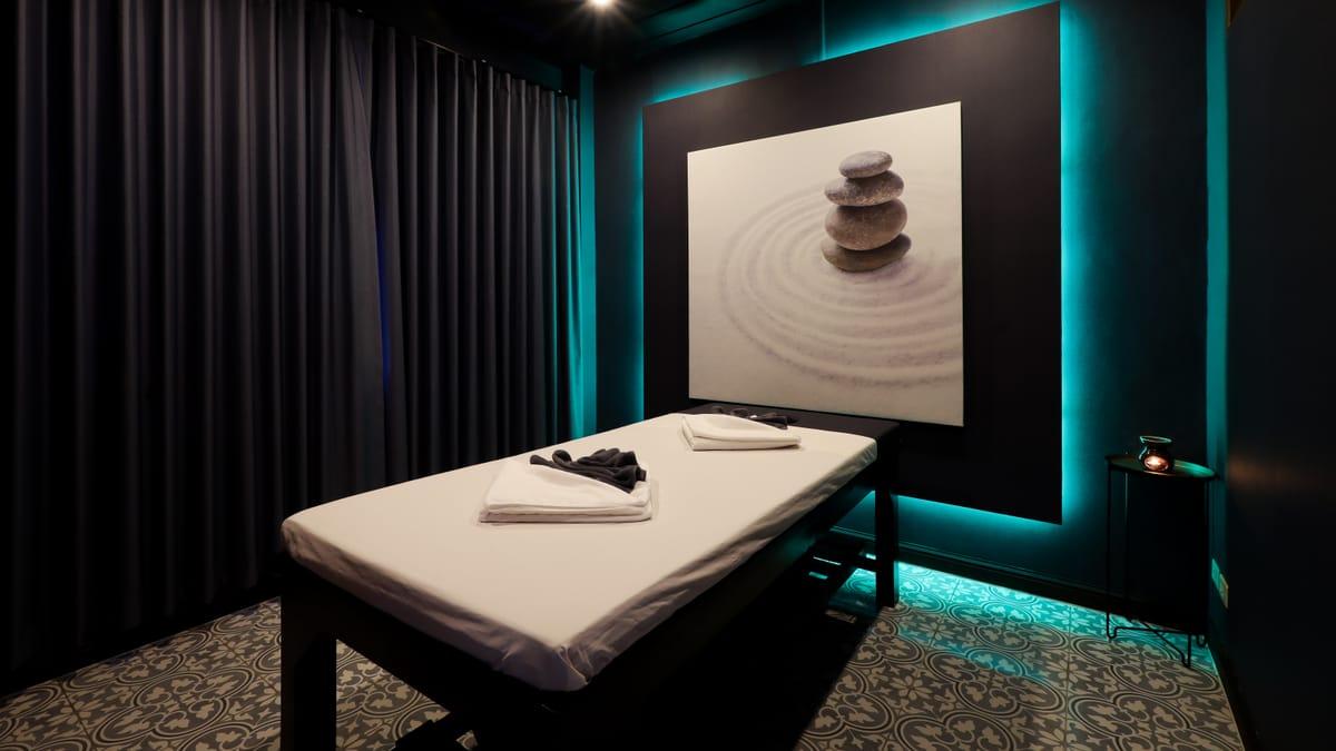 A treatment room with a padded table and a stacked-stones artwork at Jintara Rehab in Chiang Mai