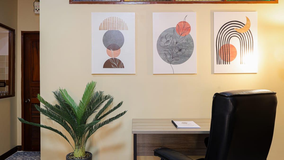 A desk and chair below framed prints at Jintara Rehab in Chiang Mai