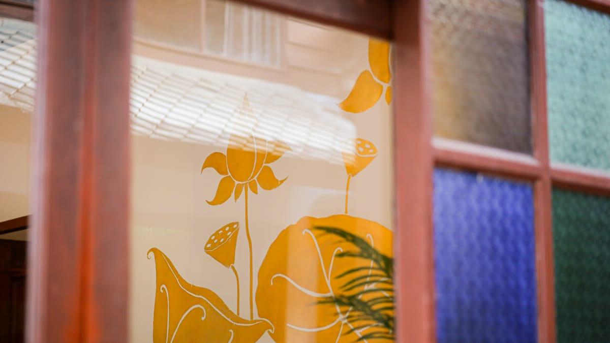 Painted lotus mural seen past a stained glass window at Jintara Rehab in Chiang Mai