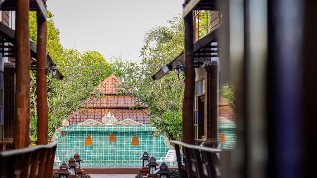 A view between two timber verandas at Jintara Rehab in Chiang Mai, towards the tiled pool fountain and garden trees
