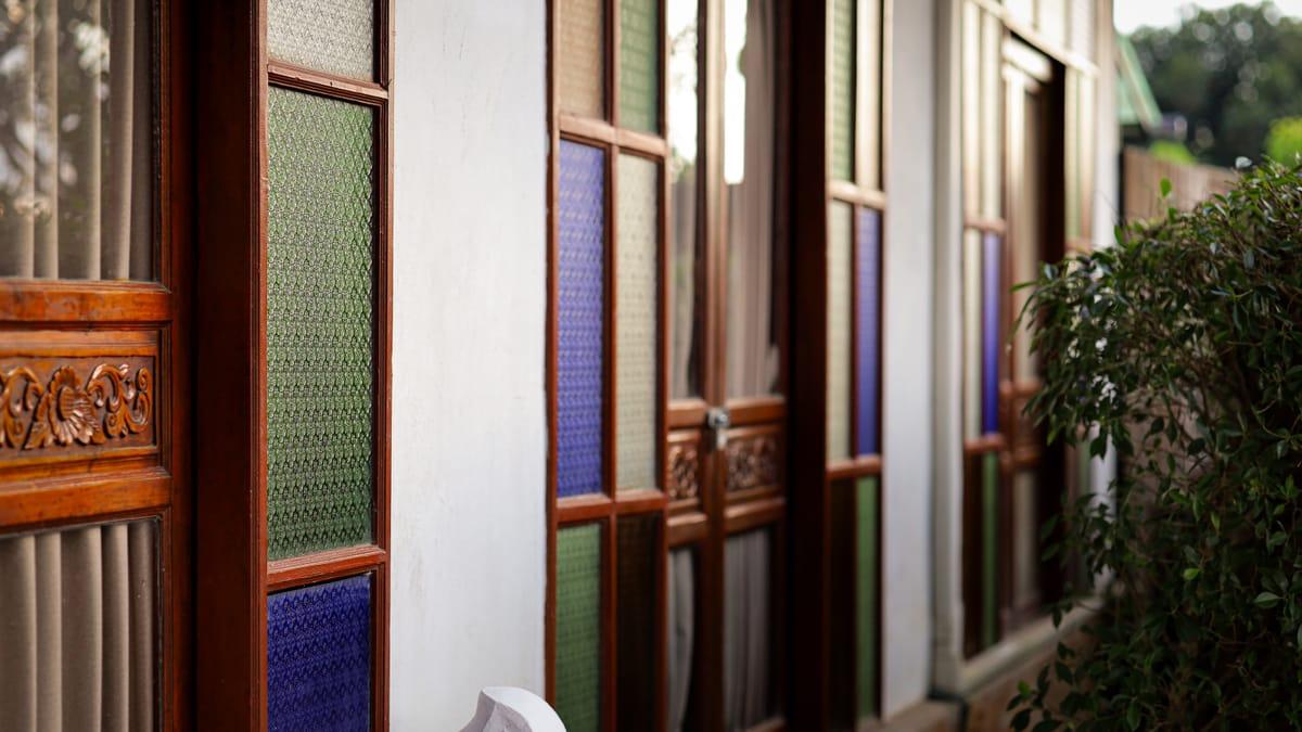 Teak doors with stained glass panels along a veranda at Jintara Rehab in Chiang Mai
