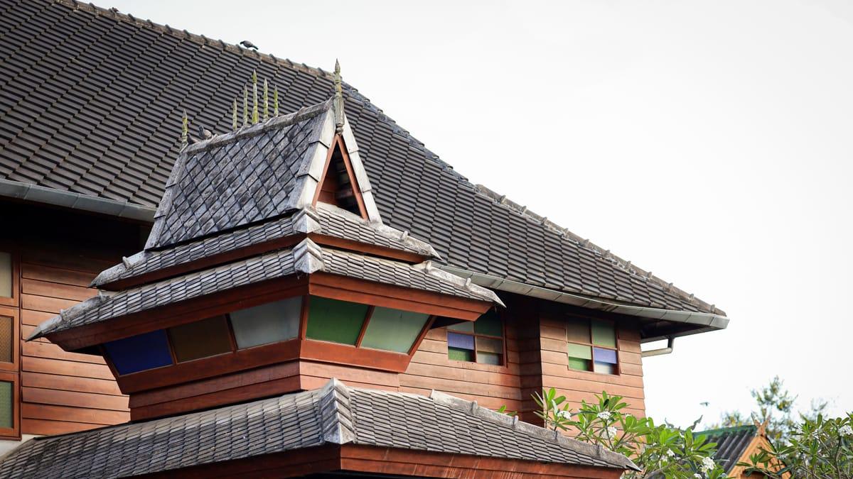 Tiered teak roof gable with coloured glass windows at Jintara Rehab in Chiang Mai