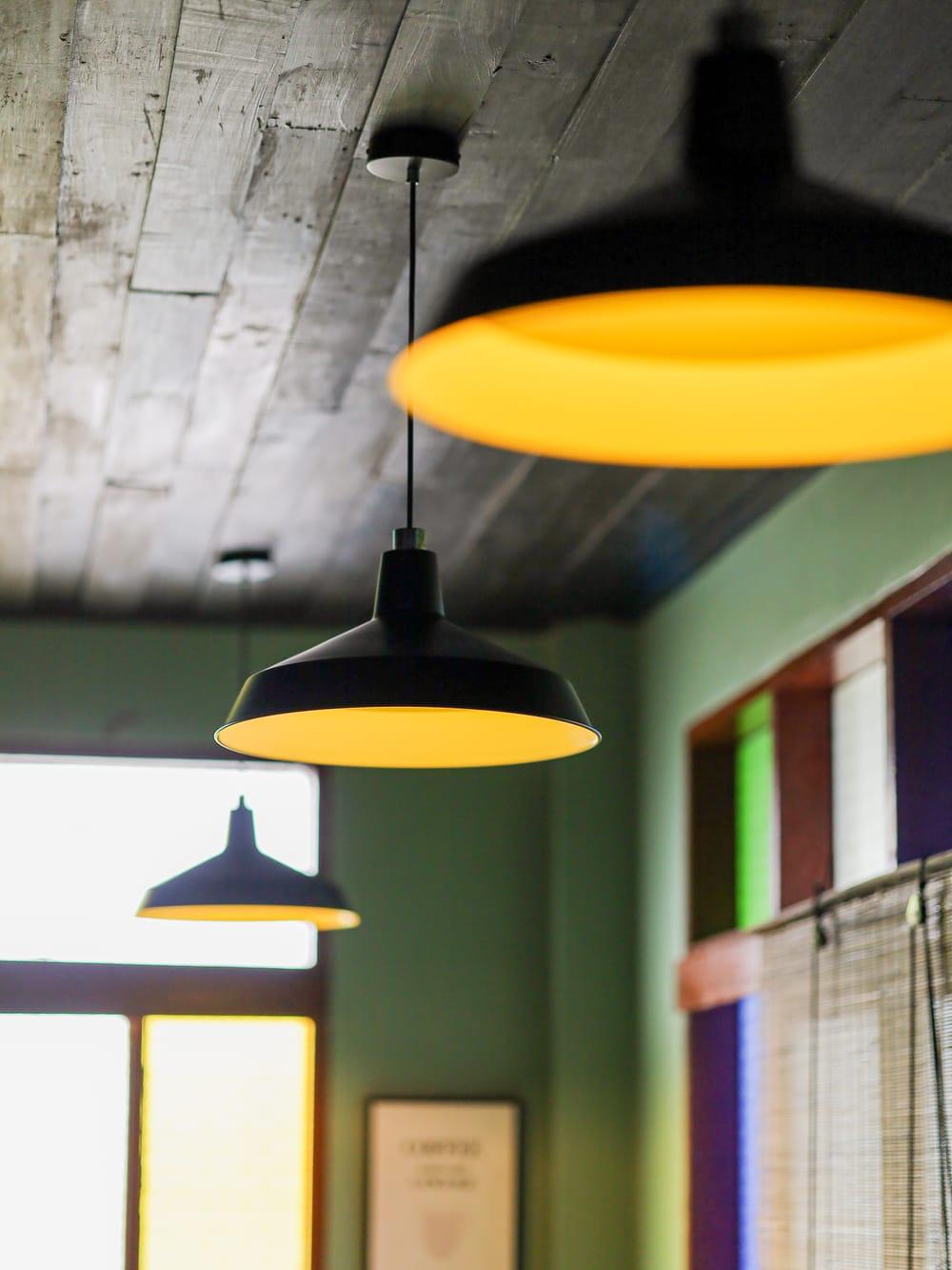 Black pendant lights with warm bulbs above a green dining room wall
