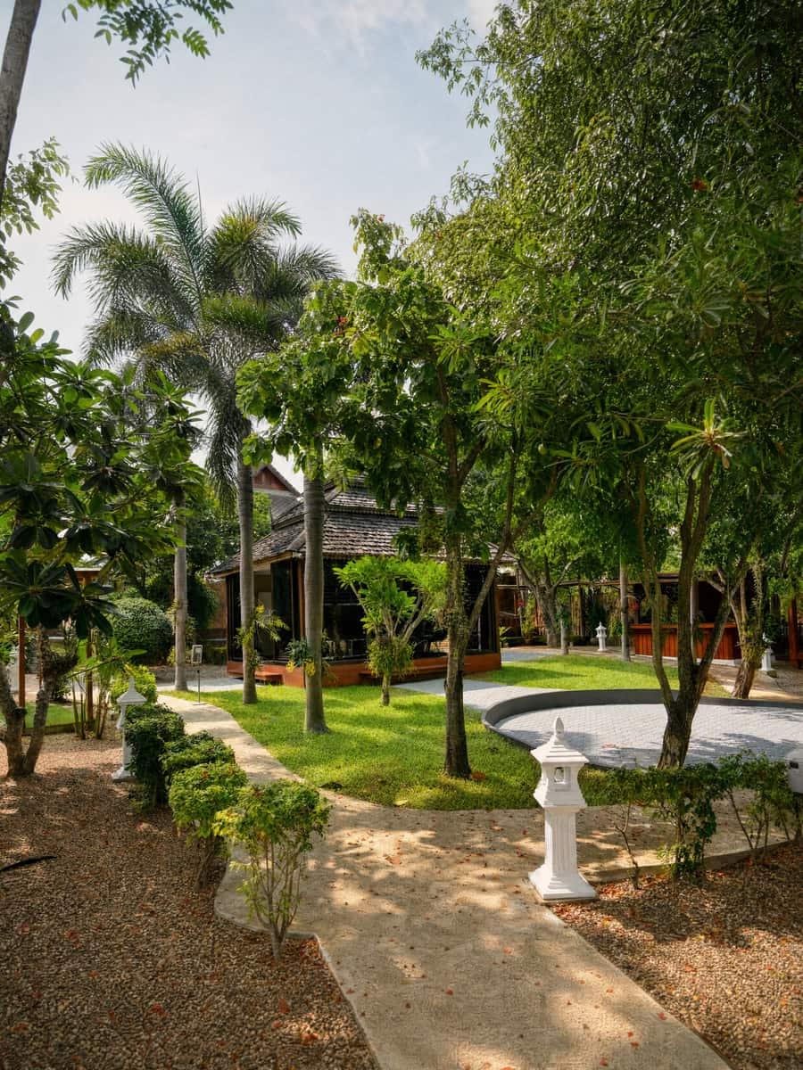 Timber sala pavilion among plumeria trees with lawn and a circular paver terrace