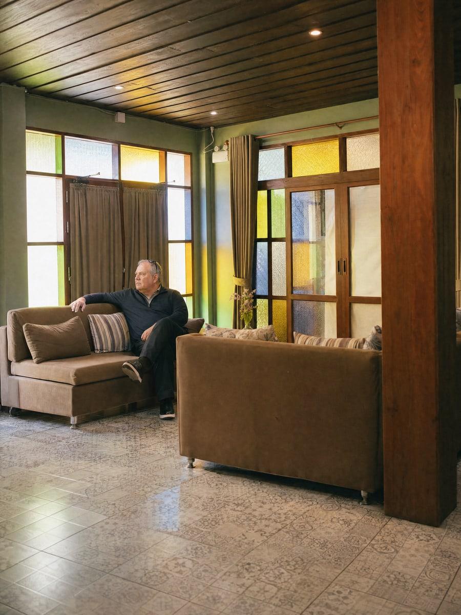 Man sitting back on a lounge sofa in warm light from tall coloured glass windows