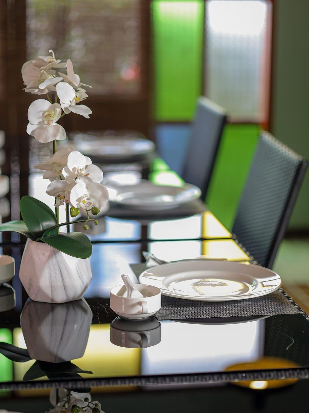 White orchid beside laid place settings on a dining table