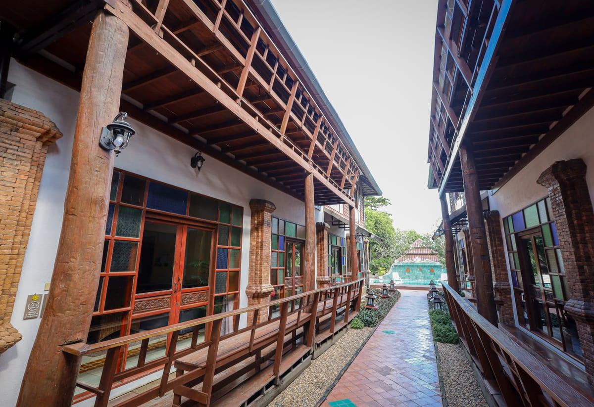 Covered Lanna-style walkway with brick columns and teak beams at Jintara Rehab in Chiang Mai