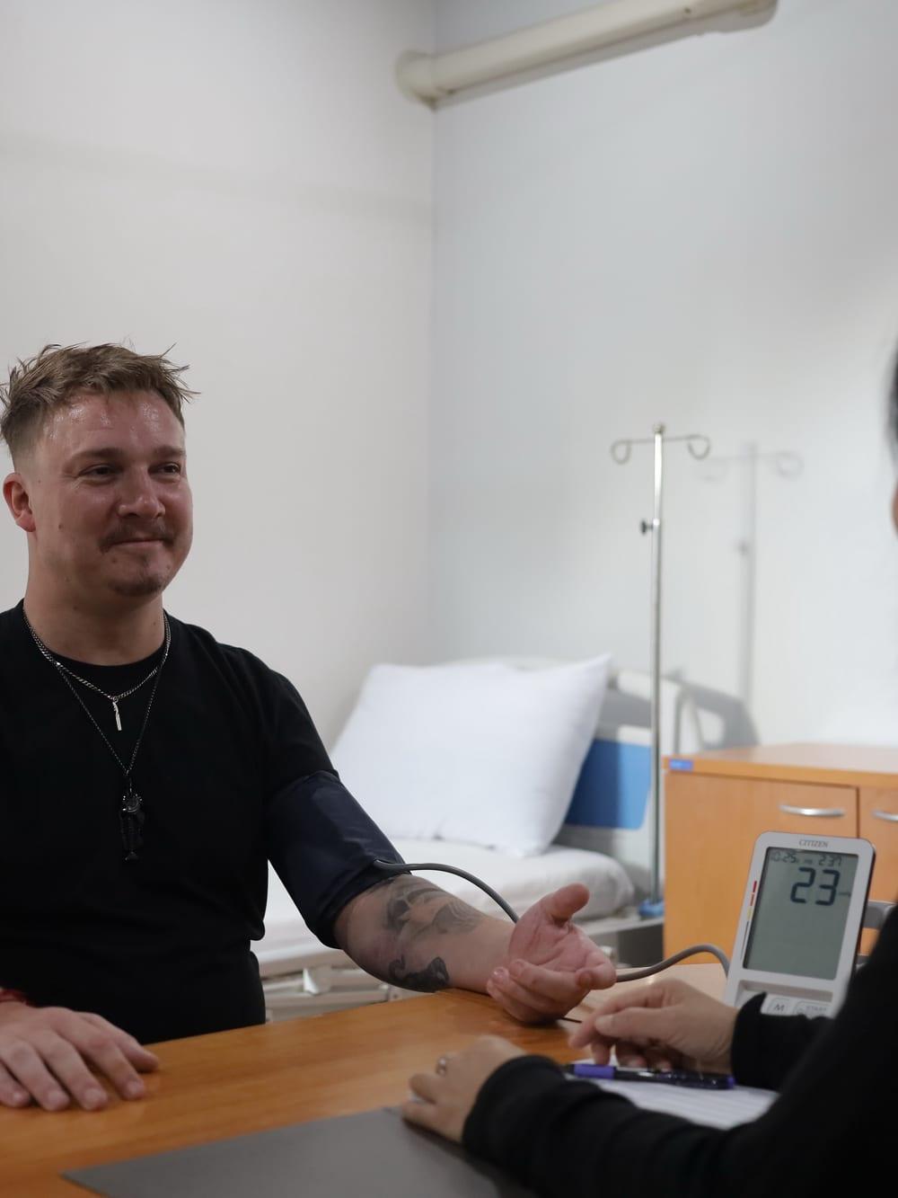 Nurse taking blood pressure reading from client in clinical room at Jintara Rehab Chiang Mai Thailand