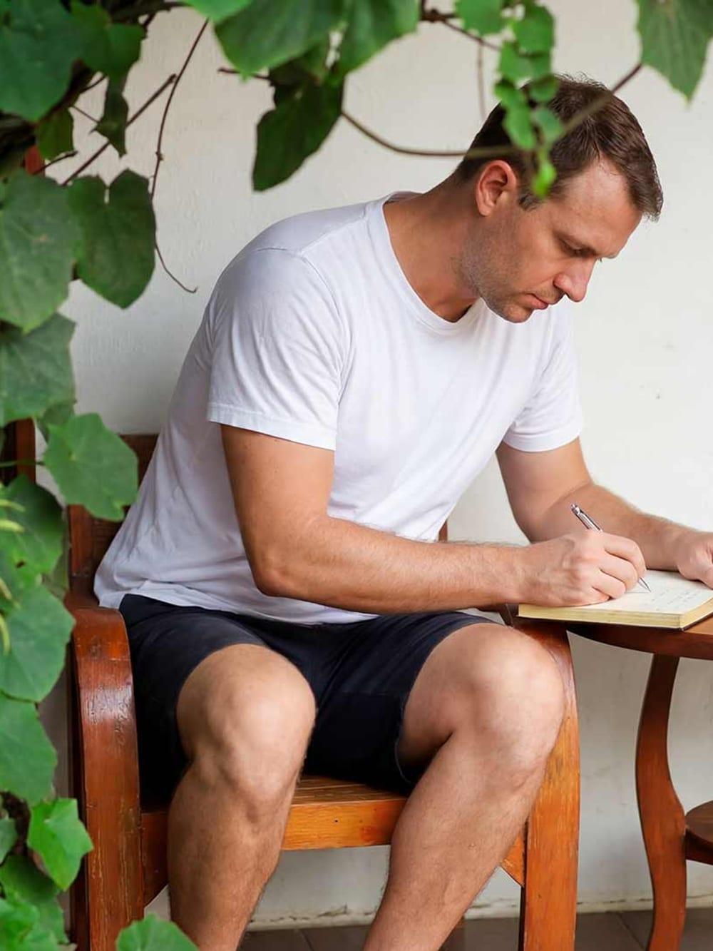 Client writing in journal on porch with tropical plants at Jintara Rehab Chiang Mai Thailand