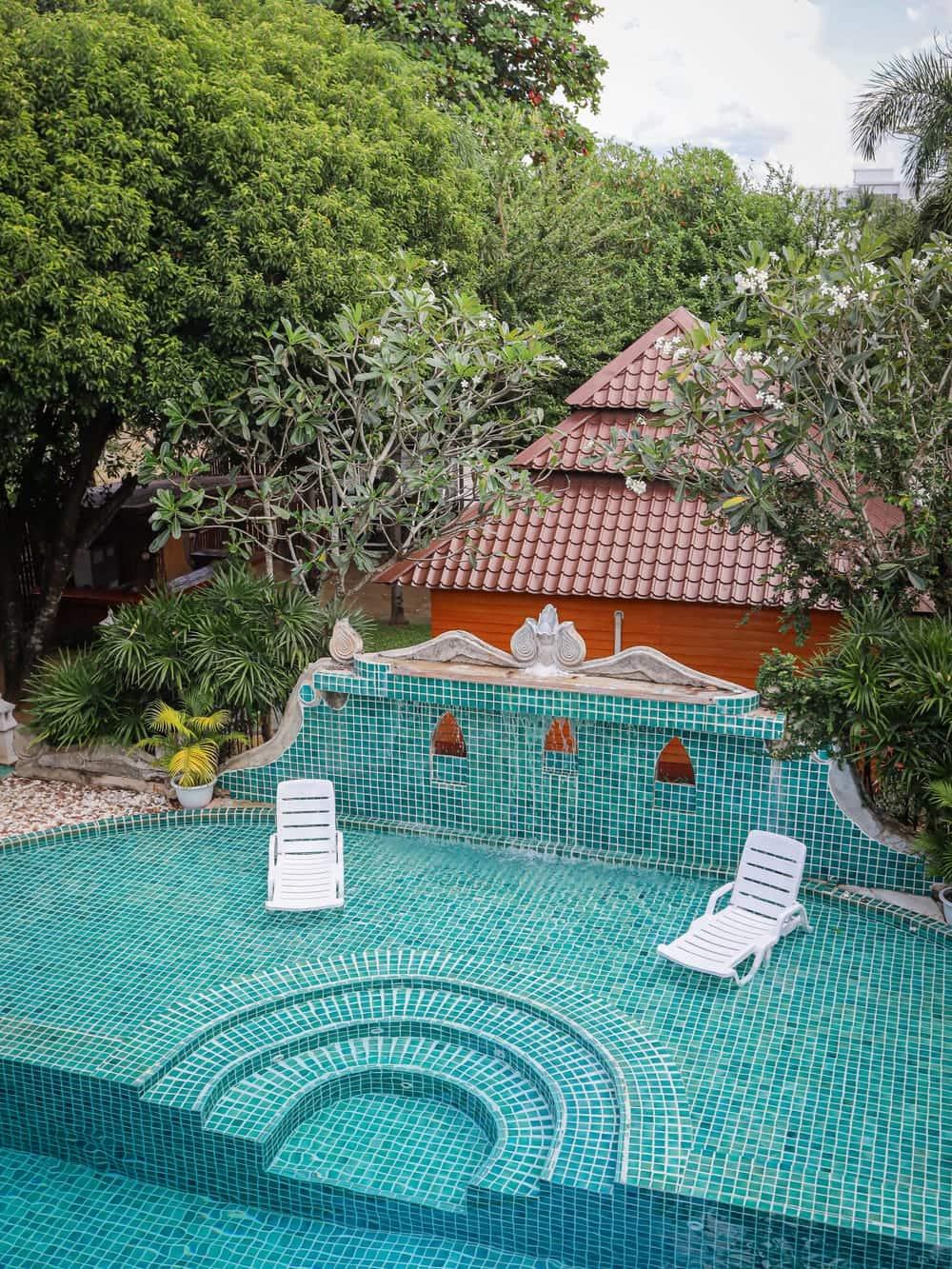 Teal pool courtyard framed by Lanna-style teak buildings at Jintara Rehab Chiang Mai Thailand