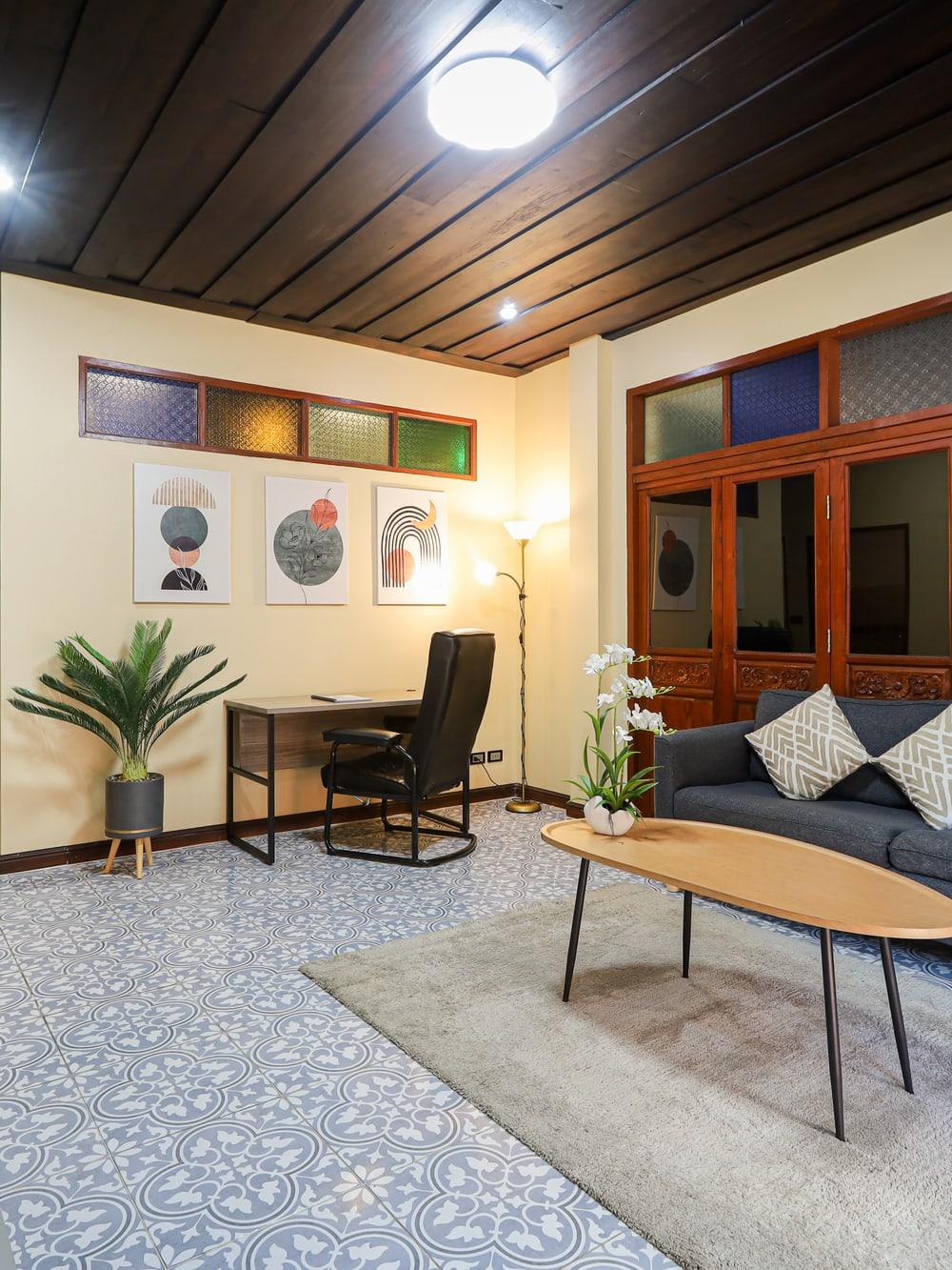 Empty sitting room with a blue-grey sofa, oval table, desk and plants at Jintara Rehab