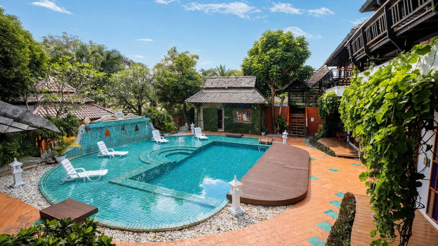 Teal mosaic pool courtyard framed by teak buildings and tropical gardens at Jintara Rehab Chiang Mai, residential treatment for Ambien and zolpidem dependence