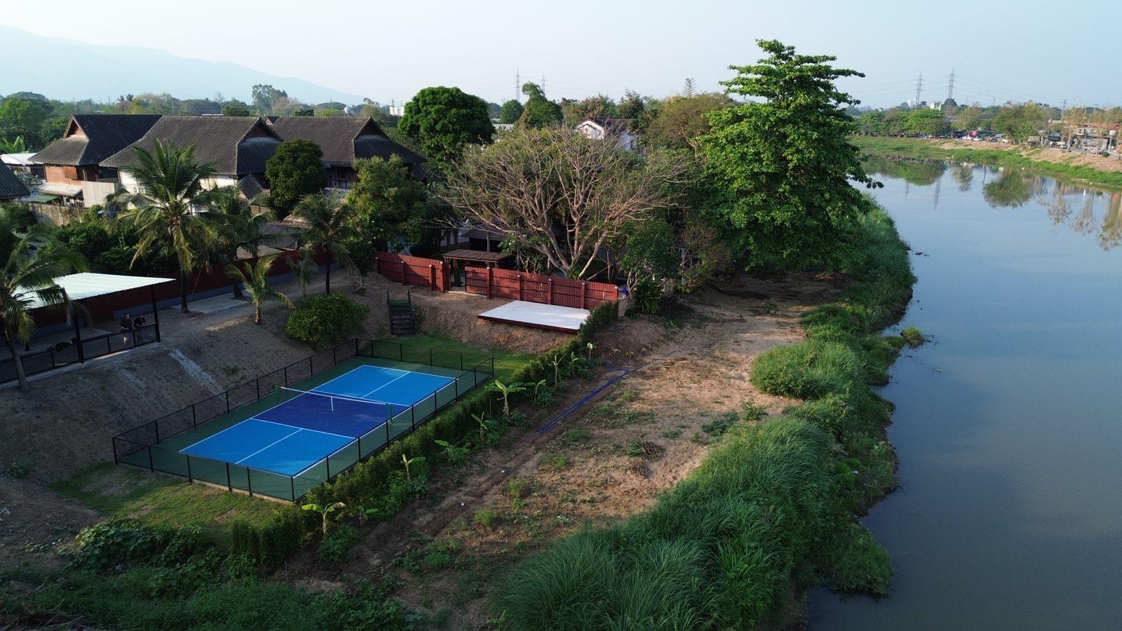 Aerial view of the Jintara Rehab property on the river outside Chiang Mai, Thailand, showing the accommodation buildings, court and riverside grounds a family is arranging admission to
