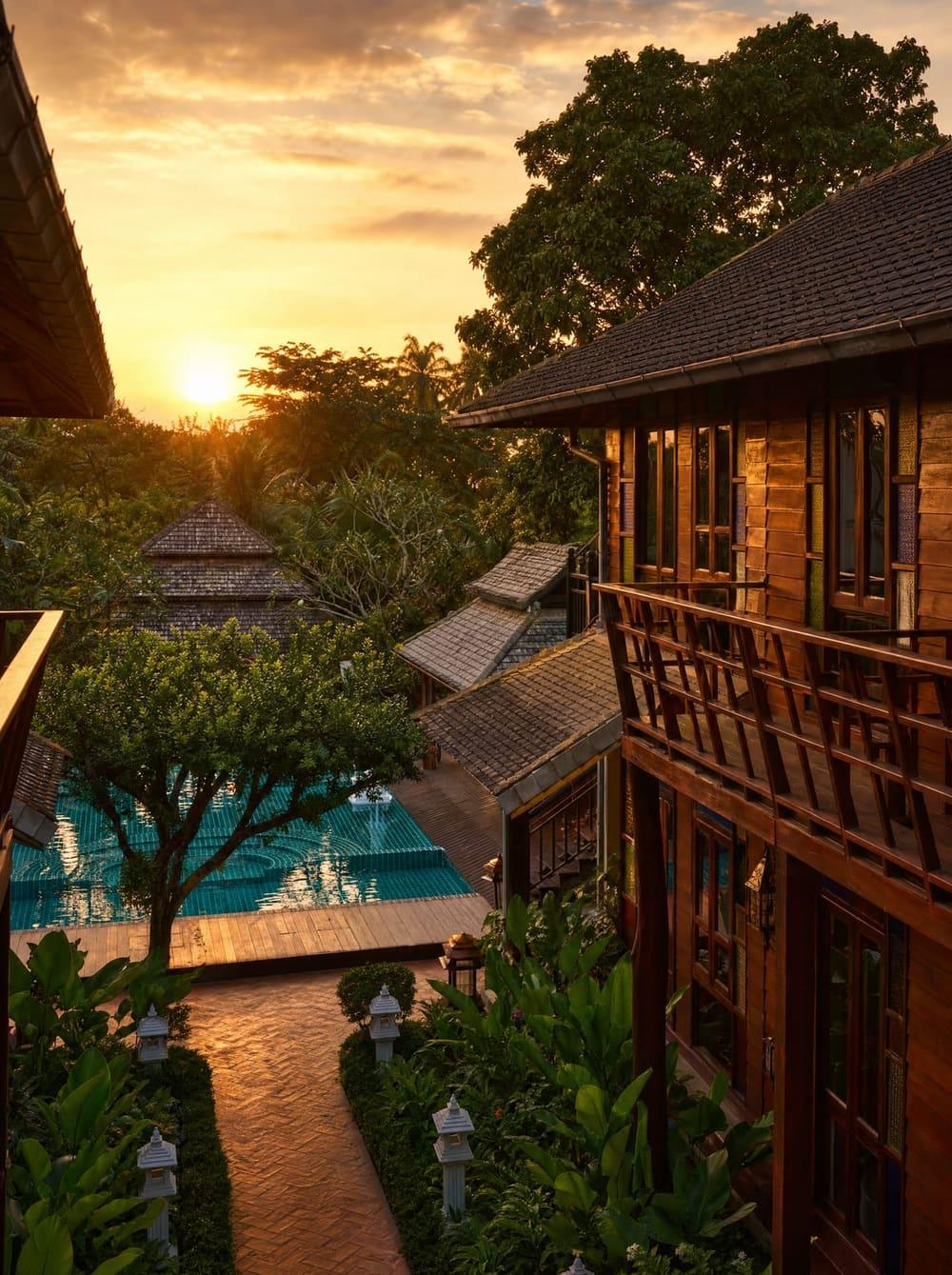 Golden hour sunset over Jintara Rehab Chiang Mai compound with teal pool and Lanna wooden buildings