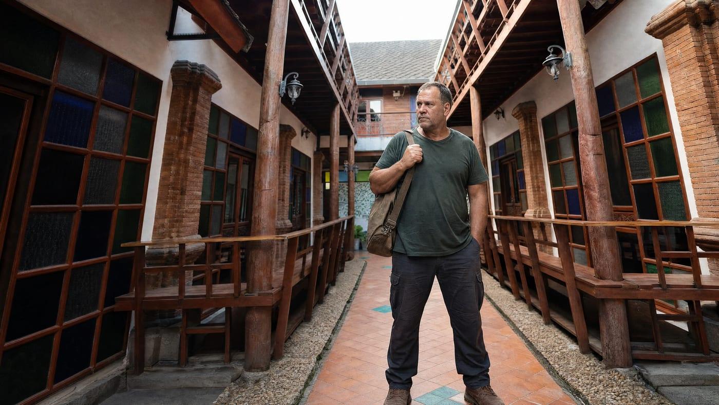 Man with a holdall standing on the tiled courtyard walkway at Jintara Rehab in Chiang Mai, the Thailand facility Australian clients travel to