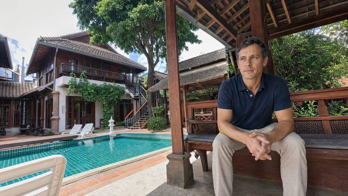 Man seated on a teak bench in the poolside sala at Jintara Rehab Chiang Mai
