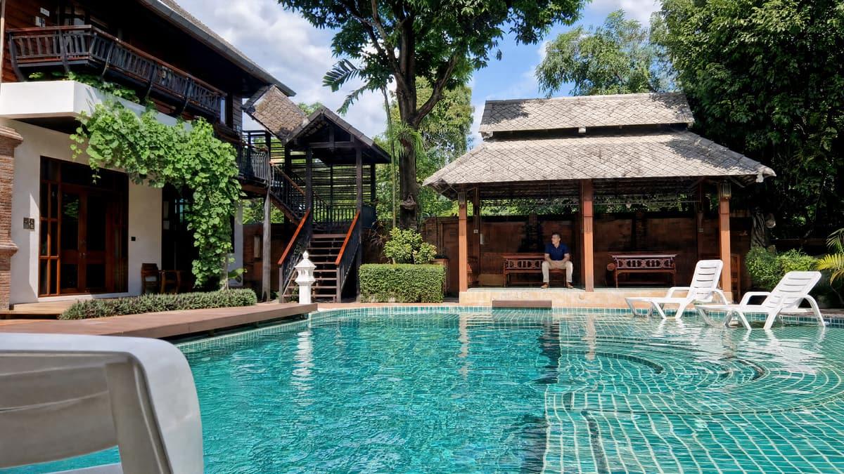 Client sitting alone in the poolside sala across the water at Jintara Rehab Chiang Mai
