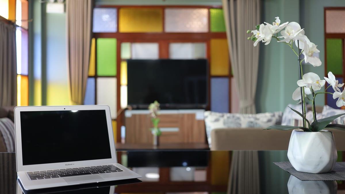 Laptop open on a lounge table beside an orchid at Jintara Rehab Chiang Mai