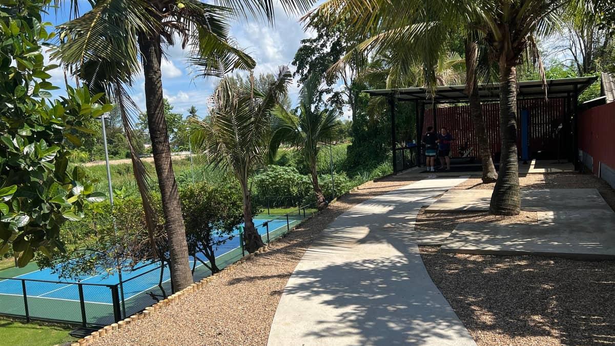 The palm-lined pathway to Jintara's covered gym beside the outdoor court