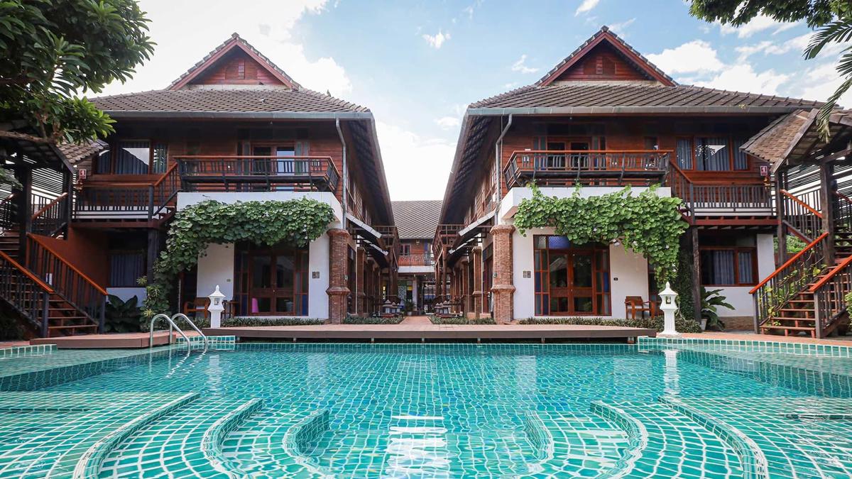 Turquoise pool and twin teak villas in the daytime grounds at Jintara Rehab Chiang Mai