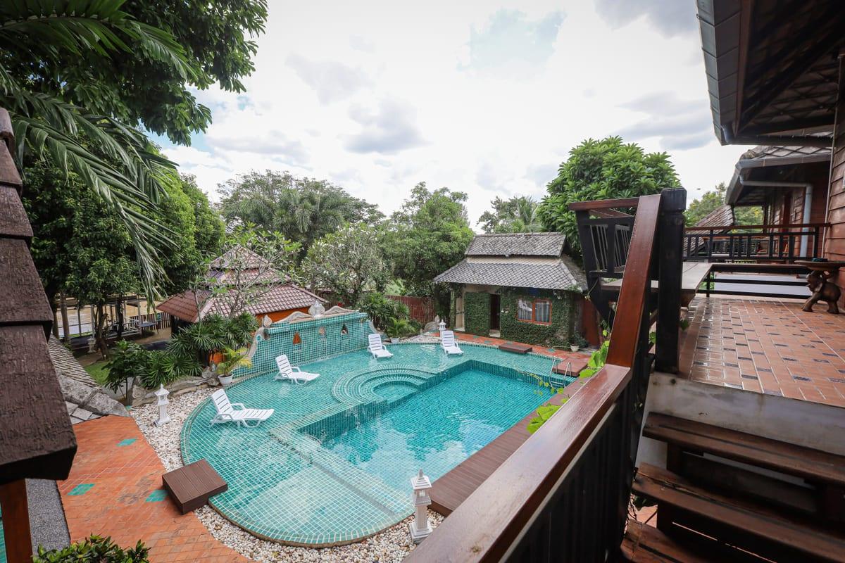 Elevated view of teal swimming pool with sun loungers and tropical trees at Jintara Rehab Chiang Mai