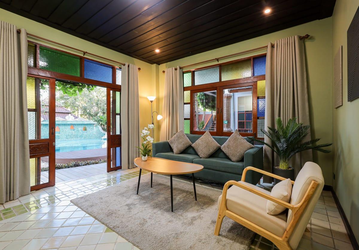 Bright lounge with green sofa and pool view at Jintara Rehab cannabis treatment facility Chiang Mai