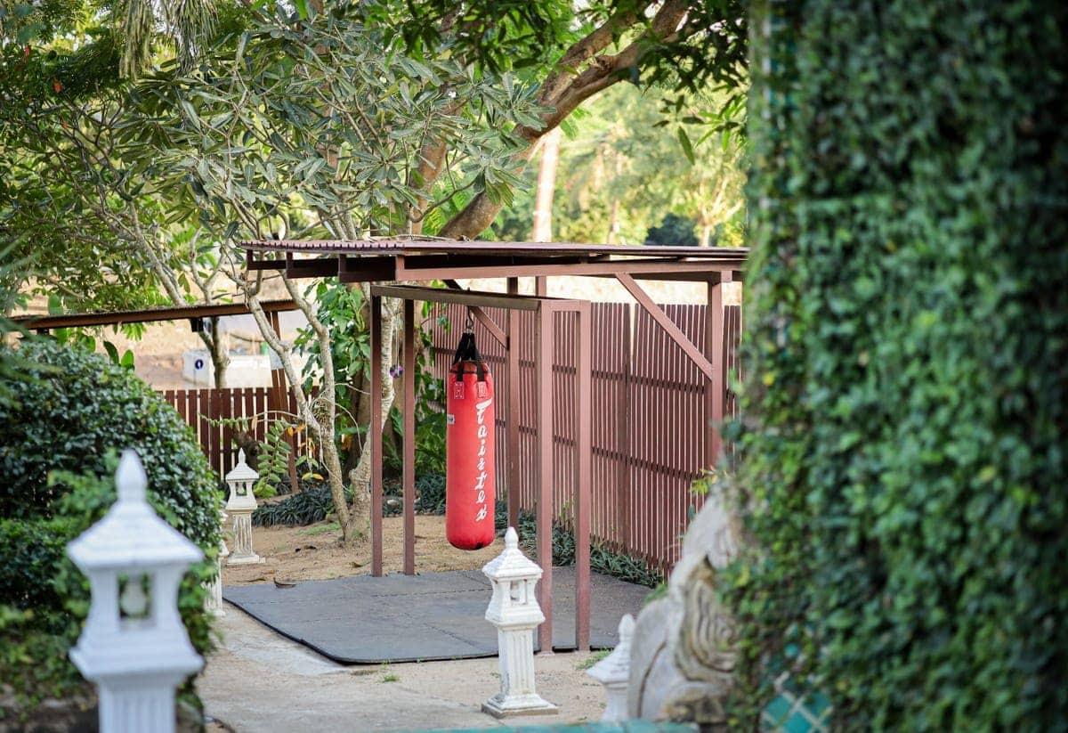 Outdoor boxing bag area at Jintara Rehab in Chiang Mai with stone lanterns and tropical garden