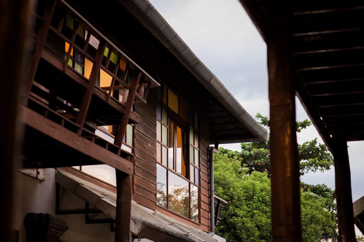 Exterior of Jintara Rehab's Lanna-style teak building showing stained glass windows in Chiang Mai