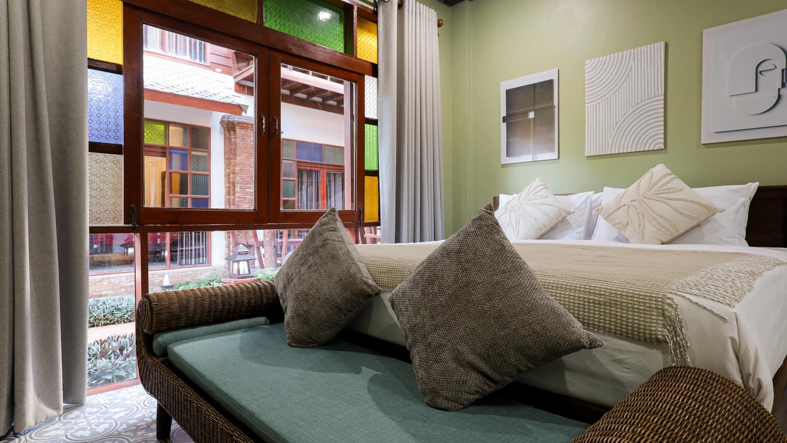 Private bedroom with stained glass windows and green sofa at Jintara Rehab facility Chiang Mai Thailand