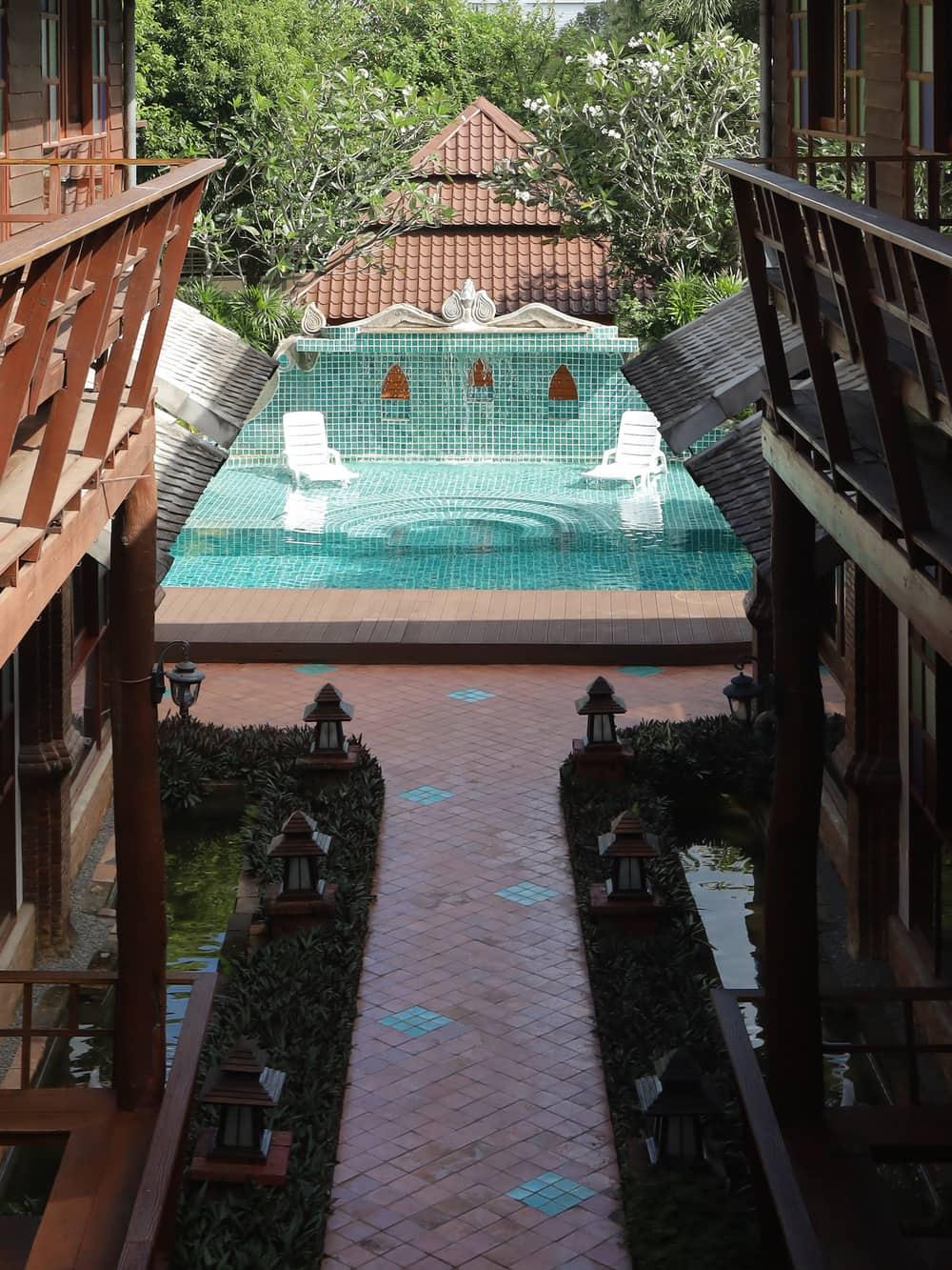 Brick walkway between the teak accommodation wings leading to the pool at Jintara Rehab Chiang Mai