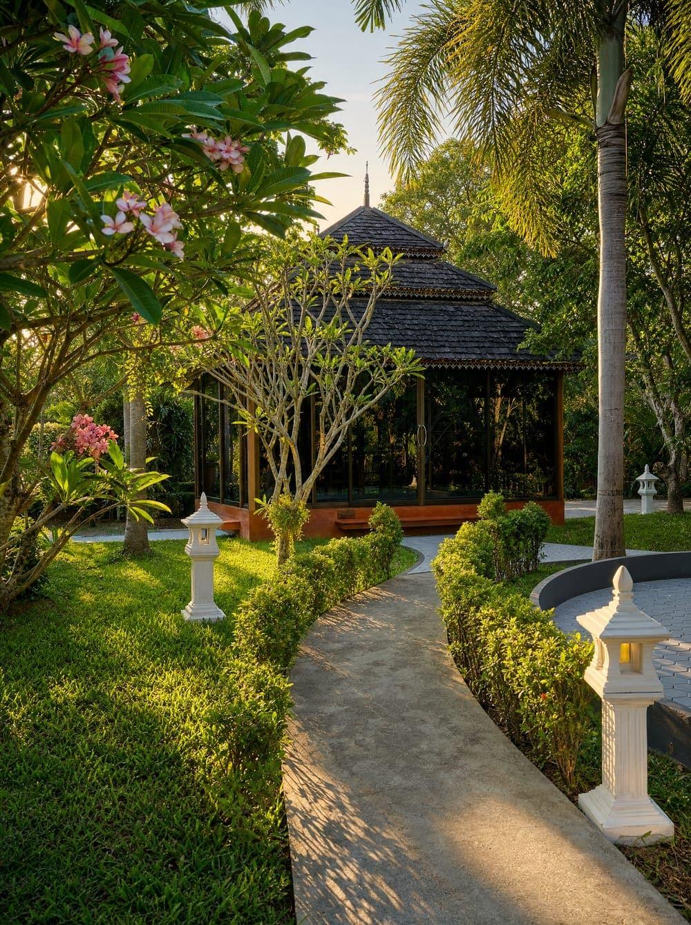 Jintara garden pavilion with stone path lanterns and frangipani bloom at Chiang Mai compound