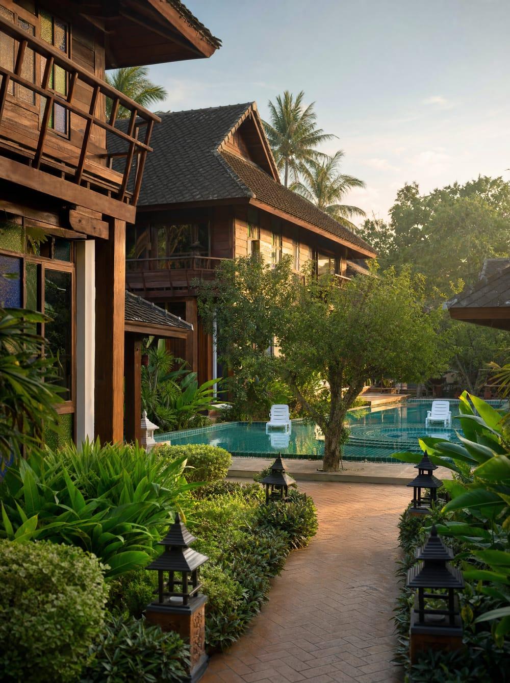 Arrival view of Jintara Rehab compound with Lanna wooden buildings and teal pool Chiang Mai