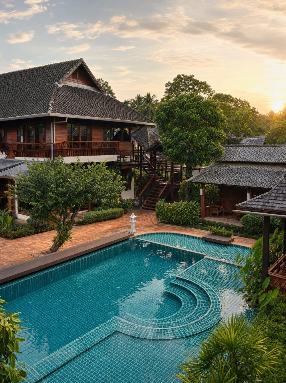 Jintara compound with teal mosaic pool and Lanna wooden buildings at sunset Chiang Mai
