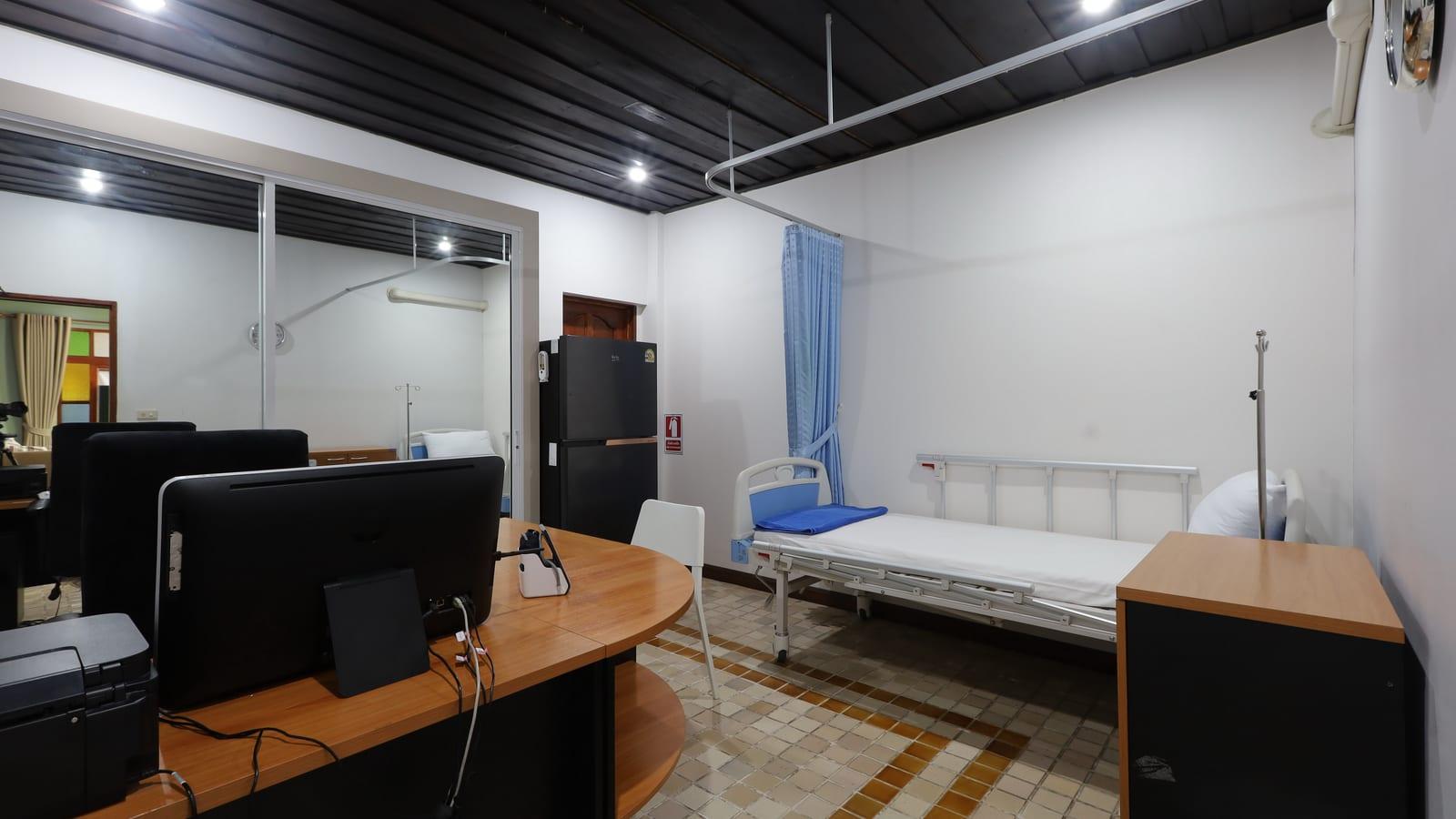 Clinical monitoring room with a medical bed and nursing desk at Jintara Rehab Chiang Mai