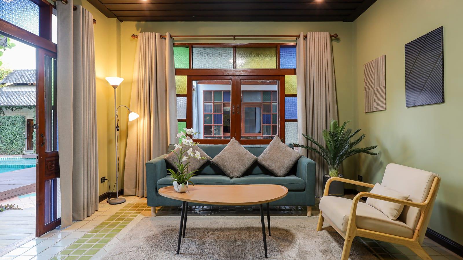 Residential lounge with sofa, armchair and stained-glass windows at Jintara Rehab Chiang Mai