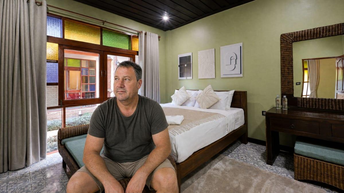 A man sitting quietly in a private room reflecting during recovery at Jintara Rehab in Chiang Mai