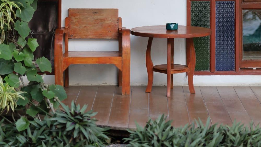 Teak chair and table on garden porch at Jintara Rehab with tropical foliage, quiet recovery space in Chiang Mai