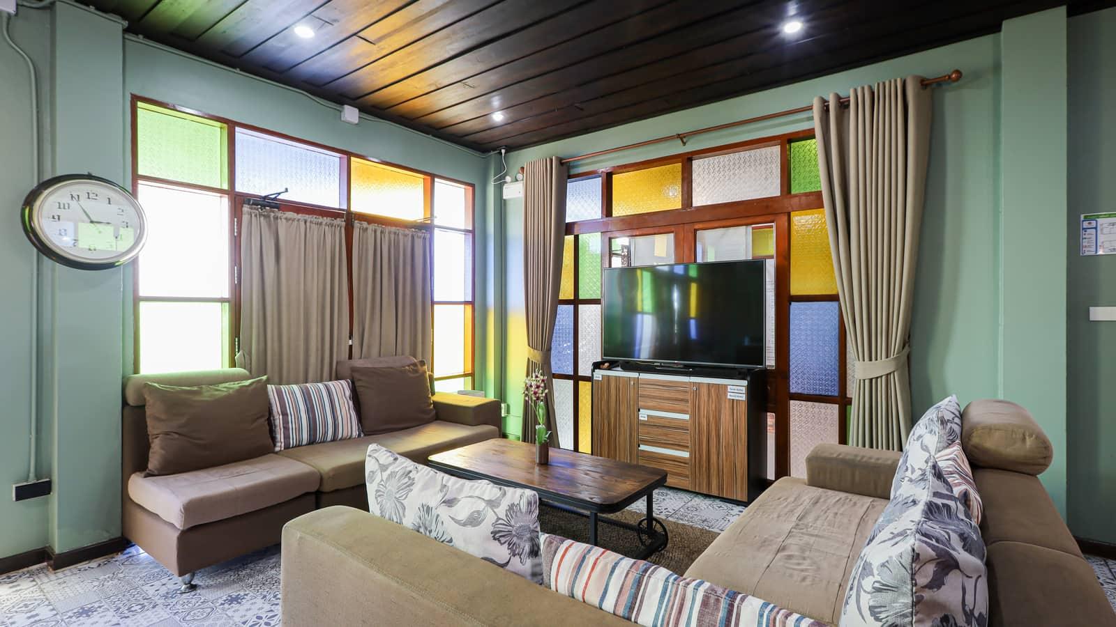 Interior lounge with teak furnishings and stained glass windows at Jintara Rehab Chiang Mai