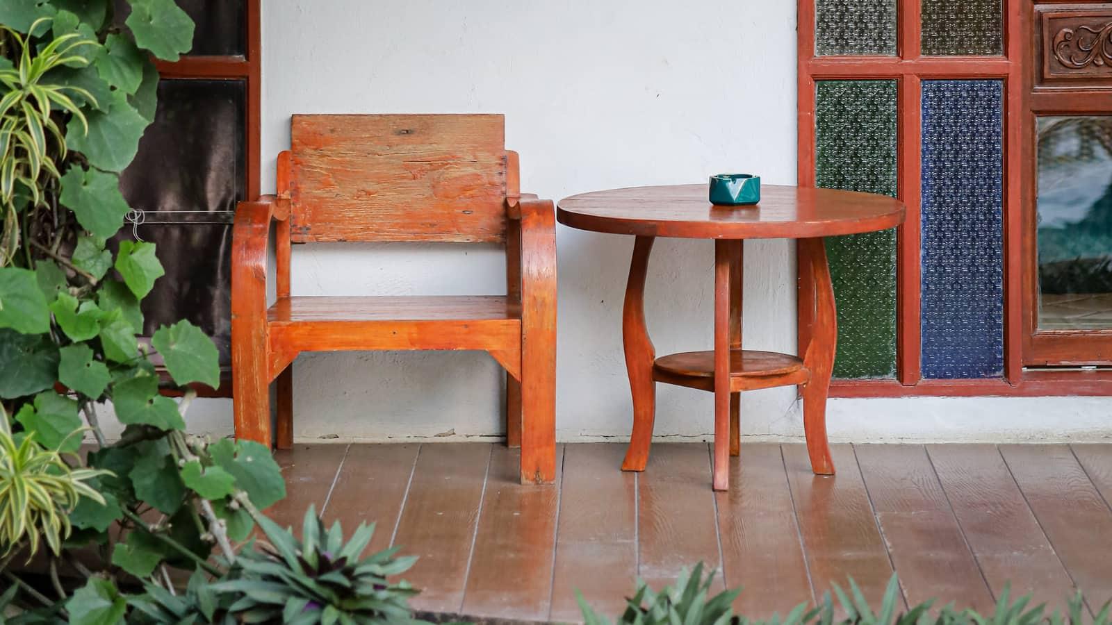 Teak armchair and round table on a veranda at Jintara Rehab with stained glass doors