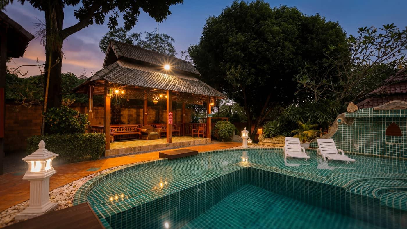 Teal mosaic pool and lit sala pavilion at dusk at Jintara Rehab Chiang Mai heroin addiction treatment facility