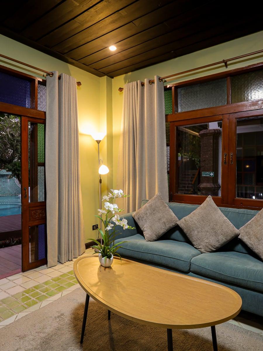 Warm evening residential lounge with teal sofa orchid and pool view at Jintara Rehab Chiang Mai therapy recovery