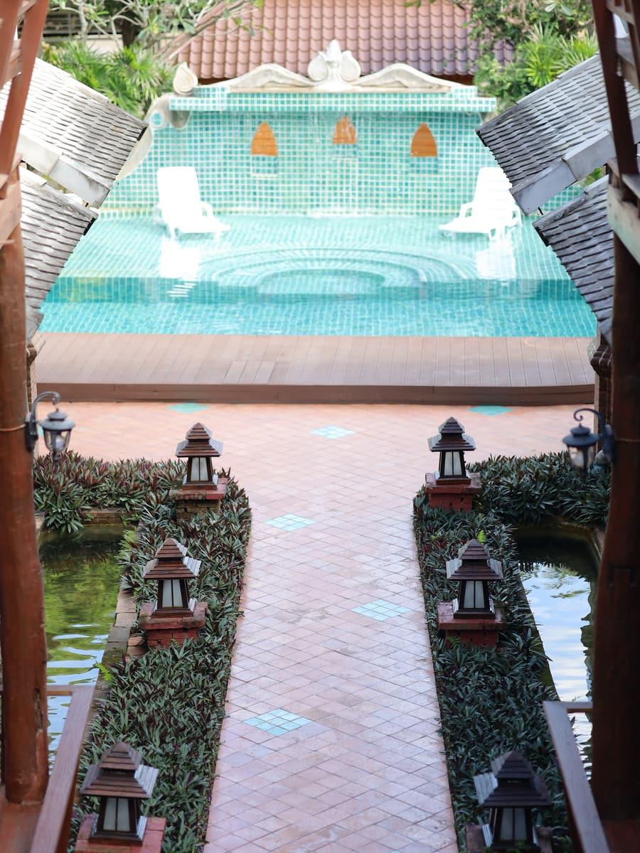 Garden walkway with Thai lanterns leading to teal pool at Jintara Rehab Chiang Mai