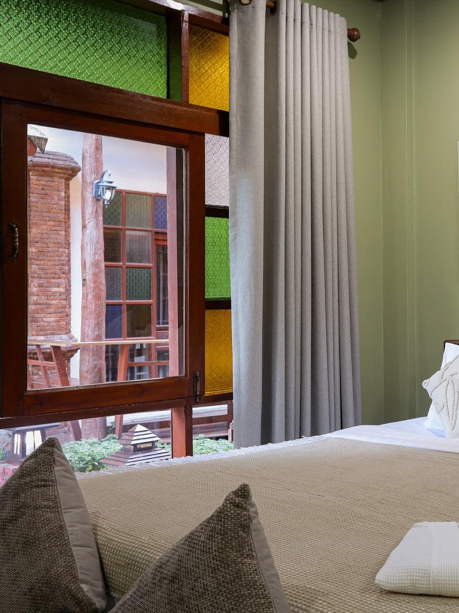 Private bedroom with green and yellow stained glass door panels at Jintara Rehab Chiang Mai heroin withdrawal recovery