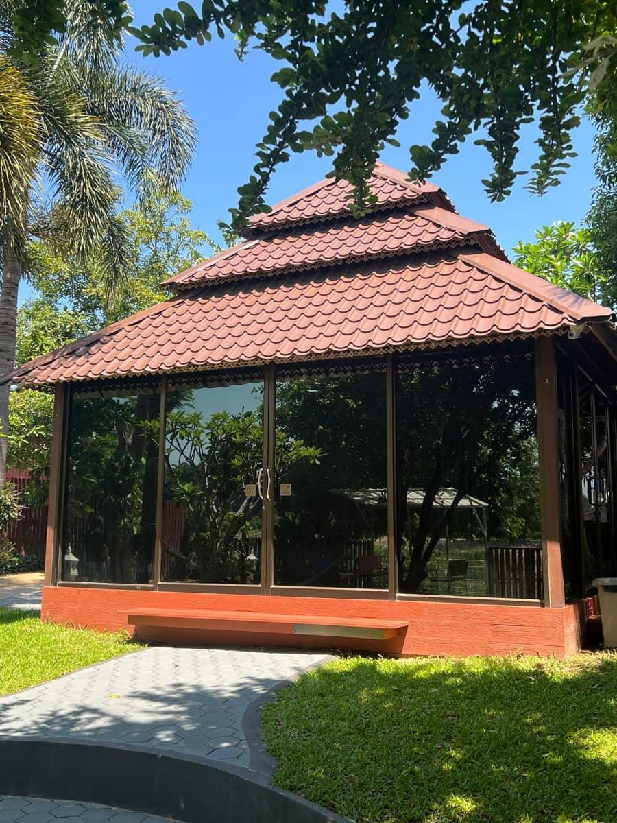 Glass therapy pavilion with Thai-tiled roof on lawn at Jintara Rehab Chiang Mai
