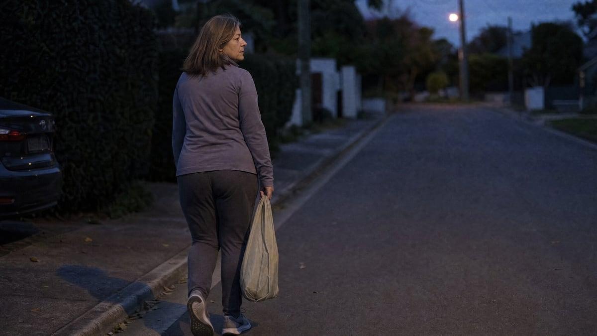 A person walks a quiet suburban street at first light carrying a small bag, one of the private routines that keep cocaine use out of a household's view