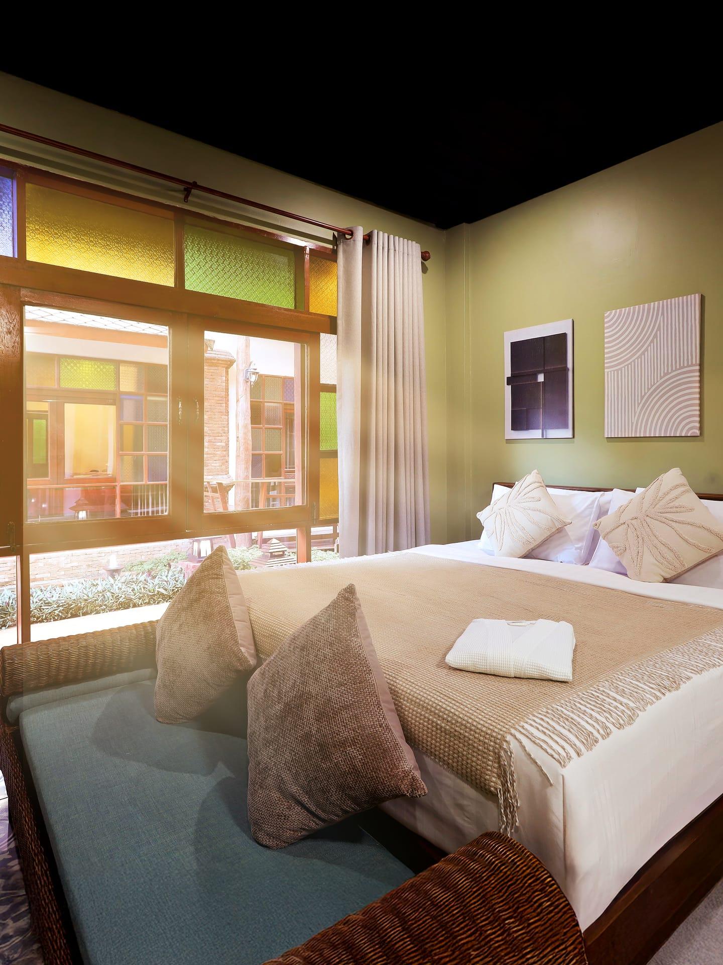 A private bedroom suite with sage walls and a stained-glass window at a Chiang Mai rehab