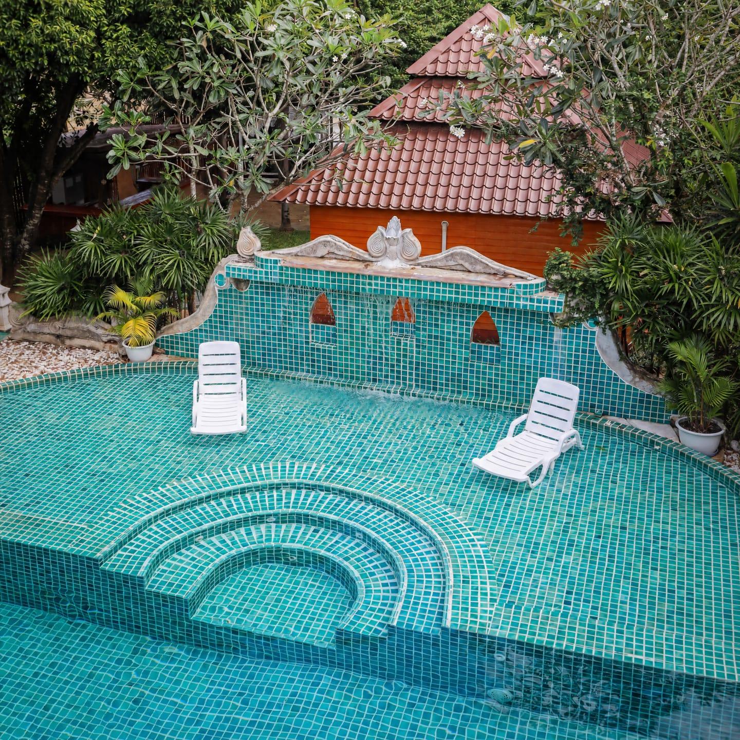 The teal mosaic pool and carved stone fountain wall at Jintara Rehab in Chiang Mai