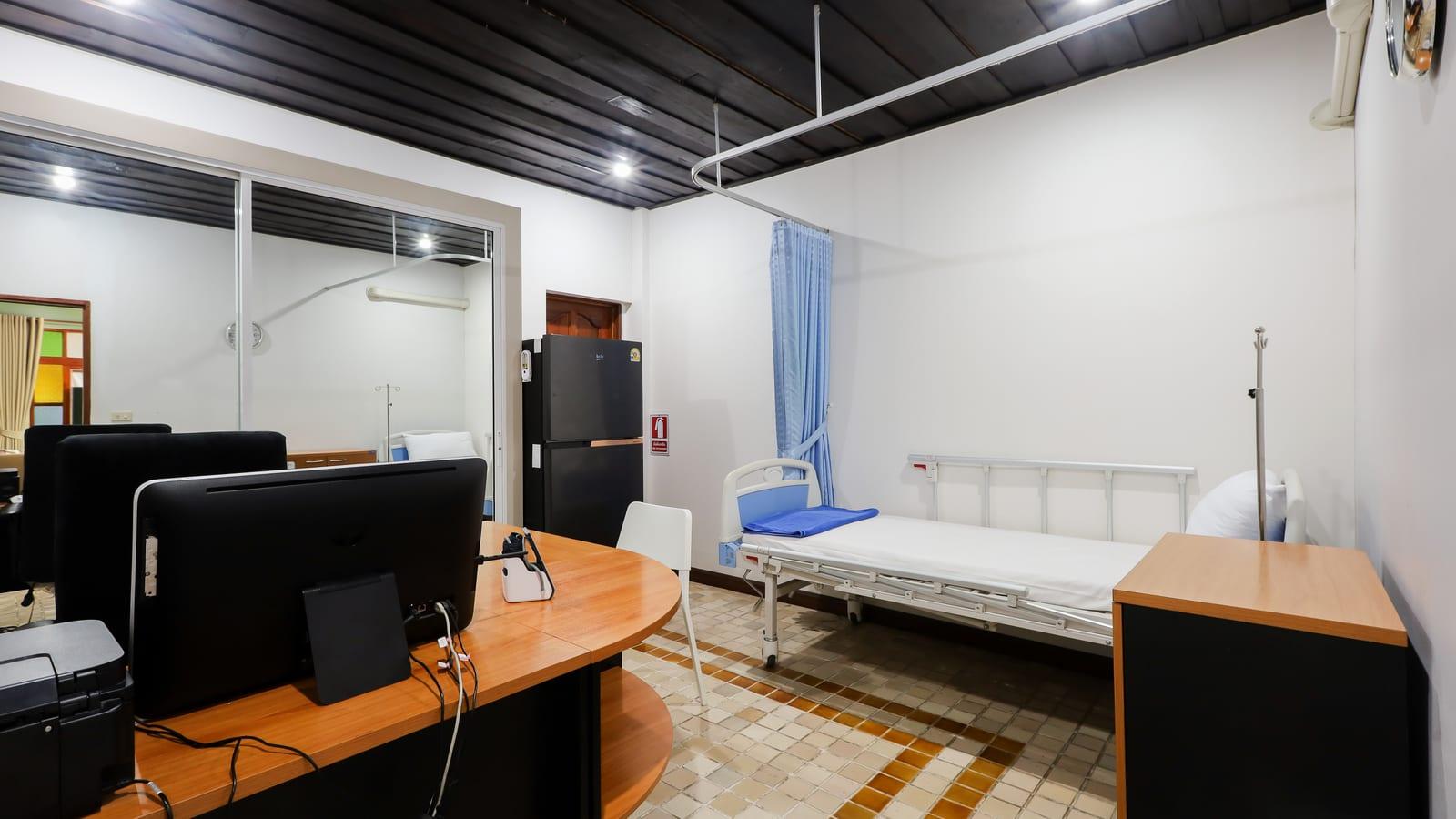 Clinical monitoring room with medical bed, IV pole and nursing desk at Jintara Rehab